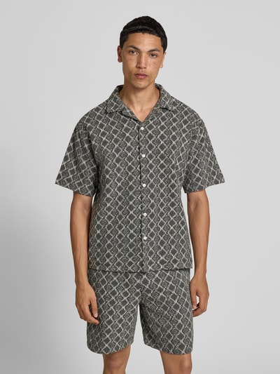 Männermodel trägt Boxy Fit Freizeithemd im Allover-Look Modell 'ZANDER' von Redefined Rebel aus Reine Baumwolle, Ganzkörperansicht von vorne. Rückenlänge bei Größe M: 65 cm, Schulterbreite bei Größe M: 51 cm, Ärmellänge bei Größe M: 25 cm, Reverskragen, graue Muster, strukturierte Oberfläche.