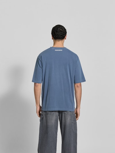 Männermodel trägt Loose Fit T-Shirt mit Rundhalsausschnitt von Dsquared2 in Blau, Used-Look, Statement-Print, Rückenlänge 72 cm, Ganzkörperansicht Rückansicht.