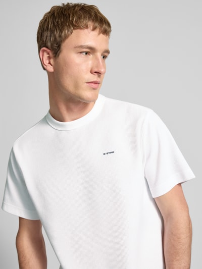 Mannelijk model draagt Regular Fit T-Shirt met structuurpatroon van G-Star Raw in wit, logo op borst, ronde hals, close-up bovenlichaam.