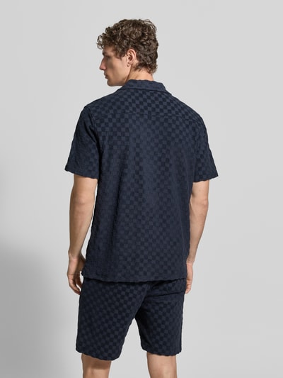 Männermodel trägt Regular Fit Freizeithemd mit Reverskragen von Lindbergh aus Baumwoll-Mix mit Knopfleiste, Rückenlänge 73 cm, Schulterbreite 48 cm, Ärmellänge 27 cm, dunkelblau kariertes Muster, Textur mit leichter Struktur, Ganzkörperansicht Rückansicht.