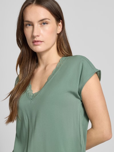 Kobiece modelka nosi Regular Fit T-Shirt mit Spitzenkragen Modell 'BELLA' von Vero Moda, kolor jednolity, jersey-stretch, dekolt V z koronką, viskoza, krótki rękaw; zbliżenie na górną część ciała