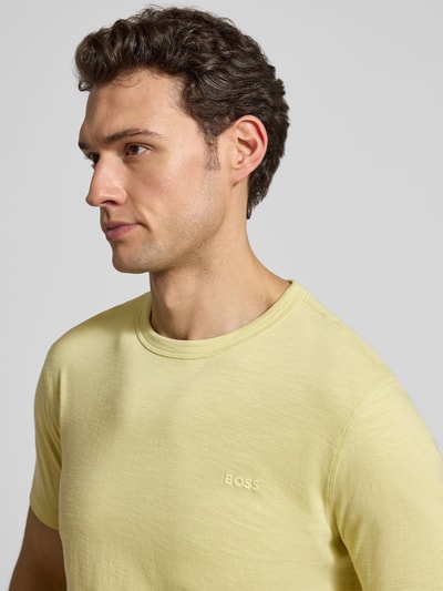 Männermodel trägt Regular Fit T-Shirt aus strukturierter Baumwolle Modell 'TEGOOD' von BOSS Orange in Uni-Gelb mit Label Print, Nahaufnahme Oberkörper.