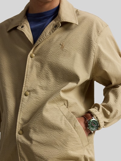 Mannenmodel draagt Regular Fit blouson uit katoenmix model 'SEERSUCKER' van Polo Ralph Lauren, look: effen, katoenmix, gestreept, platte kraag, drukknoopsluiting, gestikt logo, lange mouw, elastisch mouwboord, rompzoom met tunnelkoord, zijsteekzakken, twill-stretch; detailopname bovenlichaam.