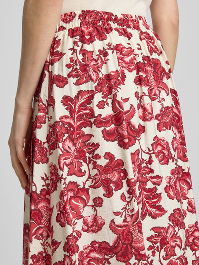 Frauenmodel trägt Midirock aus Viskose-Mix Modell 'GILVIS' von ICHI, A-Linie, Allover-Look, florales Rot auf Creme, Nahaufnahme Oberkörper.