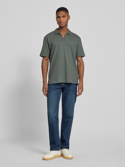 Männermodel trägt Relaxed Fit Poloshirt aus reiner Baumwolle von Marc O'Polo in Unifarben mit Polokragen und Struktur, Ganzkörperansicht von vorne.