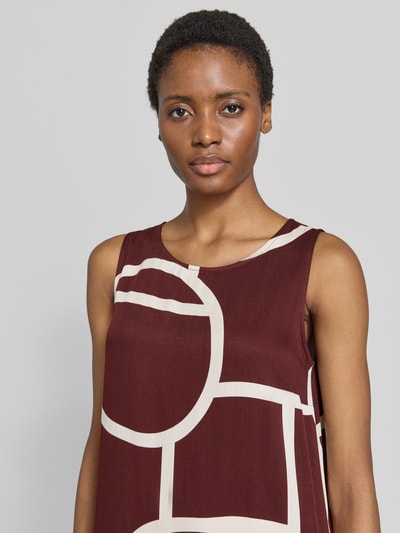 Vrouwenmodel draagt Ausgestelltes Freizeitkleid aus reiner Viskose model 'Wicy atelier' van OPUS in donkerrood met witte geometrische vormen, dames vrijetijdsjurk, detailopname bovenlichaam.