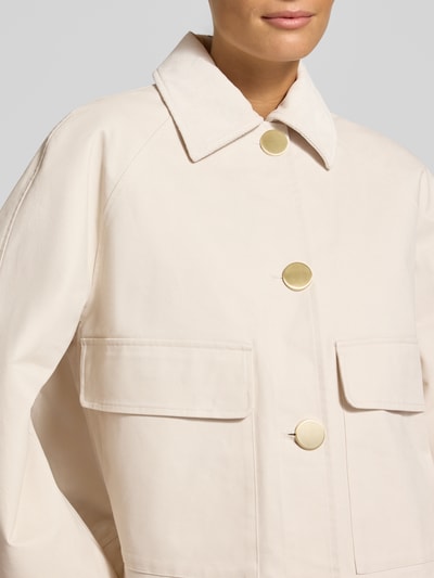 Frauenmodel trägt Jacke mit Pattentaschen von Armani Exchange in Beige, große goldene Knöpfe, Baumwoll-Elasthan-Mix, Nahaufnahme Oberkörper.
