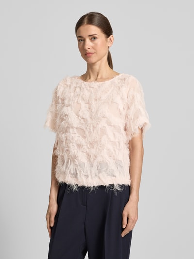 Modelka kobieca nosi Boxy Fit Blusenshirt mit Fransen-Design Modell 'MYLINE' od Selected Femme, jasnoróżowy, jednokolorowy, półprzezroczysty, krótki rękaw, strukturalny wzór z frędzlami, lekki szyfon, szeroki dekolt, widok całej sylwetki z przodu.