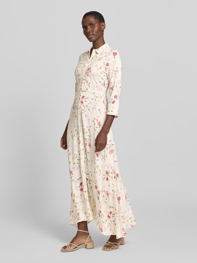 Modelka kobieca nosi Hemdblusenkleid aus Viskose mit Knopfleiste Modell 'SAVANNA' od YAS w kremowym kolorze z kolorowym kwiatowym wzorem, A-linia, długość maxi, czysta wiskoza, allover-look, długość pleców w rozmiarze S: 140 cm, szerokość w rozmiarze S: 47 cm, długość rękawa w rozmiarze S: 49 cm, pełen widok z przodu.