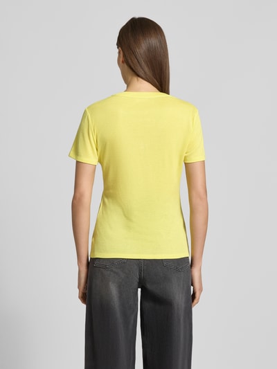 Frauenmodel trägt Regular Fit T-Shirt aus Viskose-Mix von LIU JO SPORT in Gelb mit Glitzer-Optik und Logo-Detail, Ganzkörperansicht Rückansicht.