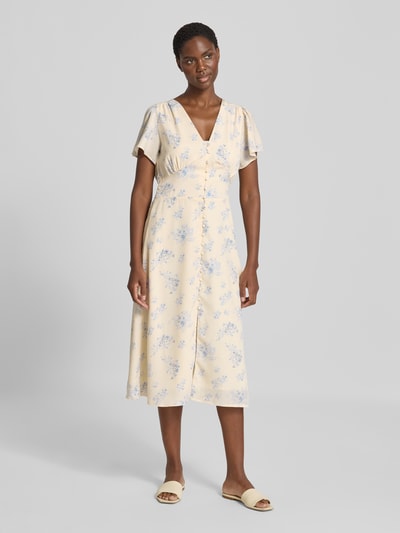 Frauenmodel trägt Midikleid mit Knopfleiste Modell 'Eleni' von Neo Noir im cremefarbenen Allover-Look mit blauen Blumen, Ganzkörperansicht von vorne.