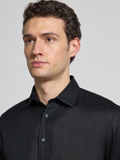 Męski model nosi Regular Fit Freizeithemd aus Leinen-Mix von Jake*s, czarny, kołnierzyk typu kent, listwa guzikowa, mieszanka bawełny i lnu, długość tyłu 75 cm, szerokość w rozmiarze M 50 cm, długość rękawów 66 cm, widok na górną część ciała z przodu