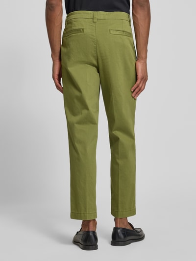 Männermodel trägt Regular Fit Chino aus Baumwoll-Mix Modell 'TAAMIR PLEATED' von Armedangels in Unifarben mit Logo-Stitching, Ganzkörperansicht Rückansicht.