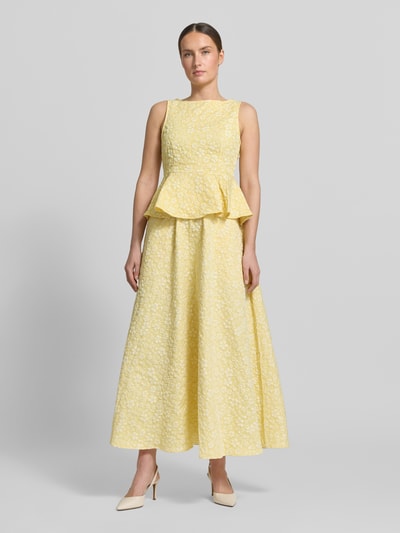Modelka kobieca nosi Ausgestellter Maxi-Rock mit Strukturmuster Modell 'FIONA' od Vero Moda, żółty, jednolity, tkanina piqué, krój regular fit, długość maxi, elastyczny pas, boczne kieszenie, tekstura jacquard, widok całej sylwetki z przodu.