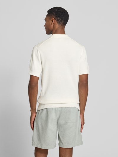 Männermodel trägt Regular Fit Strick-Poloshirt mit Strukturmuster Modell 'MOSVIK' von Casual Friday in Creme und hellgraue Shorts, Ganzkörperansicht Rückansicht.