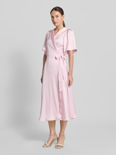 Frauenmodel trägt Midikleid in Wickel-Optik Modell 'VIENNA RAVENNA' von Vila aus rosafarbenem Satin, taillierter Schnitt, V-Ausschnitt, Ganzkörperansicht von vorne. Rückenlänge bei Größe 36: 125 cm, Brustweite: 50 cm, Ärmellänge: 30 cm.