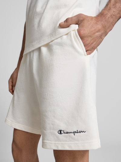 Männermodel trägt Shorts mit elastischem Bund und Label-Stitching von CHAMPION in Offwhite, Baumwoll-Mix, Nahaufnahme Oberschenkel.
