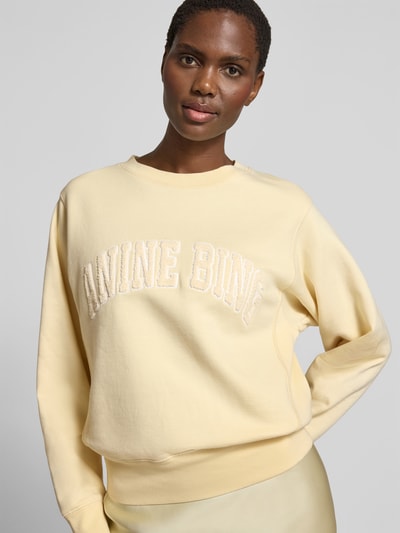 Frauenmodel trägt Regular Fit Sweatshirt mit Logo-Detail von Anine Bing in Hellgelb, reine Baumwolle, Rundhalsausschnitt, Nahaufnahme Oberkörper.