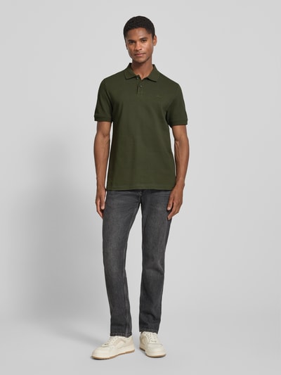 Männermodel trägt Regular Fit Poloshirt aus reiner Baumwolle von s.Oliver RED LABEL in Dunkelgrün, Ganzkörperansicht von vorne.