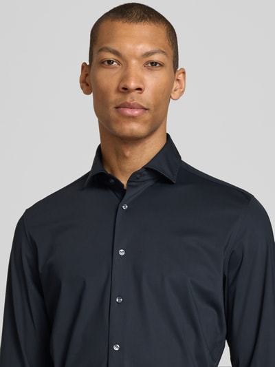 Männermodel trägt Slim Fit Business-Hemd mit Haifischkragen von SEIDENSTICKER, Material-Mix mit Stretch-Anteil, Nahaufnahme Oberkörper.