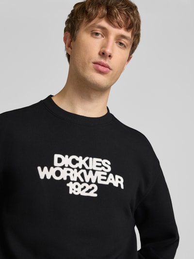 Männermodel trägt Sweatshirt mit Label-Print Modell 'TORREY' von DICKIES, Baumwoll-Mix, Schwarztöne, lockerer Schnitt, Nahaufnahme Oberkörper.
