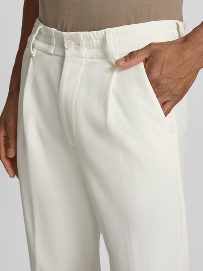 Männermodel trägt Slim Fit Stoffhose mit Bundfalten Modell 'Chasy' von Drykorn aus Baumwoll-Mix, Nahaufnahme Oberkörper. Kontext: Herren Stoffhose, Bundfalten, Elastischer Bund, Eingrifftaschen, Gesäßtaschen, Knopf-Reißverschluss, Bundweite 36 cm, Innenbeinlänge 68 cm.