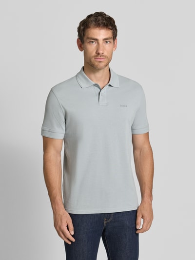 Männermodel trägt Relaxed Fit Poloshirt aus reiner Baumwolle Modell 'Prime' von BOSS für BOSS Orange, hellgrau, glatte Struktur, Ganzkörperansicht von vorne.