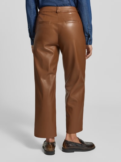 Frauenmodel trägt Flared Fit Stoffhose in Leder-Optik von MORE & MORE in Braun, glatte Textur, mit Eingrifftaschen, Ganzkörperansicht Rückansicht.
