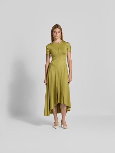 Frauenmodel trägt Midikleid mit verlängerter Rückseite von Victoria Beckham, olivgrün, elastischer Material-Mix, Kurzarm, Ganzkörperansicht von vorne.