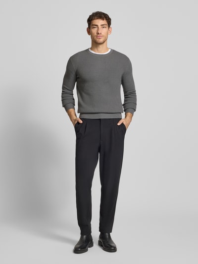 Męski model nosi Regular Fit Strickpullover aus Woll-Baumwoll-Mix Modell 'Connor' von Tiger Of Sweden, kolor szary, prążkowane wykończenia, okrągły dekolt, długość tyłu w rozmiarze M: 65 cm, długość rękawów w rozmiarze M: 69 cm, mieszanka wełny i bawełny, widok całej sylwetki z przodu.