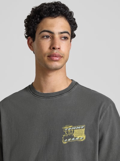 Männermodel trägt Regular Fit T-Shirt aus reiner Baumwolle Modell '90s' von Tommy Jeans, unifarben, Label Print, Nahaufnahme Oberkörper.