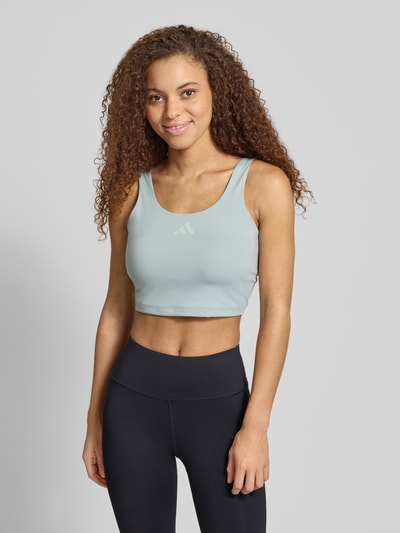Frauenmodel trägt Slim Fit Sport BH mit Logo-Print von adidas Sportswear in Twist-Optik und Rundhalsausschnitt, Ganzkörperansicht von vorne