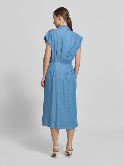 Frauenmodel trägt mittellanges blaues Kleid mit kurzen Ärmeln, glatter Struktur und lockerer Passform, Ganzkörperansicht Rückansicht.