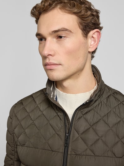 Mannelijk model draagt 'Slim Fit Steppjacke mit gefüttertem Kragen' van Christian Berg Men, olijfgroen, gewatteerd, detailopname bovenlichaam.