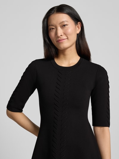 Frauenmodel trägt Minikleid aus Viskose-Mix Modell 'Abito Maglia' von Liu Jo White in Schwarz mit Zierbesatz, Nahaufnahme Oberkörper.