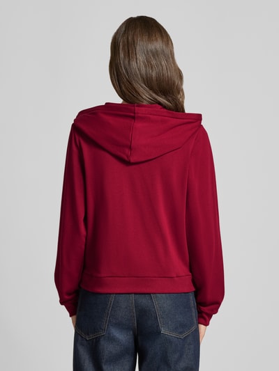 Männnermodel trägt Regular Fit Sweatjacke aus Baumwoll-Mix von HUGO in Dunkelrot, glatte Struktur, kombiniert mit blauer Jeans, Ganzkörperansicht Rückansicht, Damen Sweatjacke.