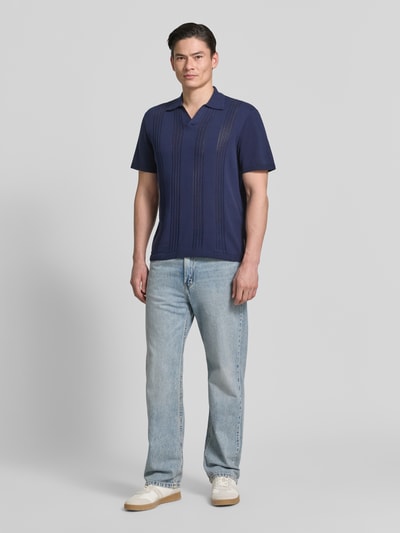 Männermodel trägt Relaxed Fit Poloshirt aus reiner Baumwolle von Armedangels in Optik: Unifarben, Feinstrick, Ganzkörperansicht von vorne.