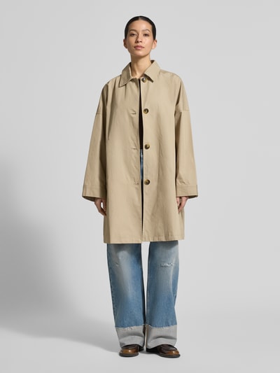 Frauenmodel trägt Regular Fit Mantel mit Umlegekragen Modell 'Zofia' von FREE/QUENT, beigefarbener Baumwoll-Mix mit Knopfleiste und Eingrifftaschen, lockere Passform. Ganzkörperansicht von vorne.
