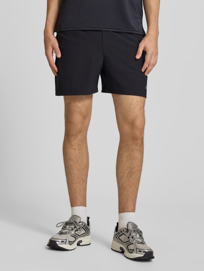Mężczyznamodel nosi szorty z elastycznym pasem i logo od New Balance, krój regular fit, tunel, Szerokość w rozmiarze M: 39 cm, Długość wewnętrzna nogawki: 12 cm, Ganzkörperansicht von vorne.