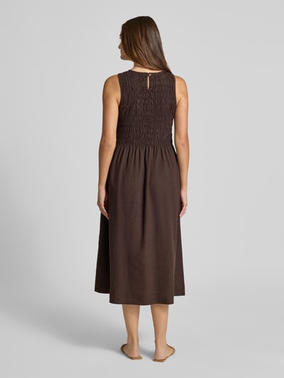 Frauenmodel trägt Midikleid aus Baumwoll-Leinen-Mix mit Eingrifftaschen von Smith and Soul, braun, taillierte Passform, Ganzkörperansicht Rückansicht. Rückenlänge bei Größe S: 120 cm, Brustweite bei Größe S: 36 cm, Rundhalsausschnitt, rückseitiger Schlüsselloch-Ausschnitt, feine Struktur.