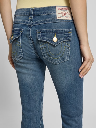 Frauenmodel trägt Low Rise Flared Jeans mit Eingrifftaschen Modell 'JOEY' von TRUE RELIGION aus Baumwoll-Mix im Used-Look, Detailaufnahme Rückansicht.