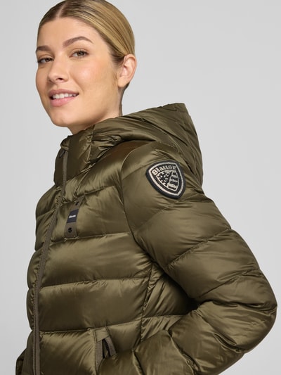 Modelka nosi kurtkę puchową z efektem pikowania, detal z logo, kaptur, zamek błyskawiczny dwustronny, Model 'Charme' od Blauer USA, Szerokość w rozmiarze S: 44 cm, Szerokość klatki piersiowej w rozmiarze S: 43 cm, Długość tyłu w rozmiarze S: 62 cm, Długość rękawów w rozmiarze S: 62 cm, krój taliowany, ujęcie: zbliżenie na górną część ciała