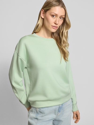 Kobiece model prezentuje bluzę z mieszanki wiskozy z dodatkiem streczu, krój relaxed fit, model 'Ima' od MSCH Copenhagen, okrągły dekolt, jasny kolor, gładka tekstura, cała sylwetka z przodu