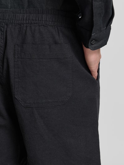 Männermodel trägt Leinenshorts mit elastischem Bund von GAP aus Leinen-Baumwoll-Mix, Loose-Fit, schwarze Farbe, Detailaufnahme Rückansicht. Bundweite 42 cm, Innenbeinlänge 17 cm, Gesäßtasche und Eingrifftaschen.
