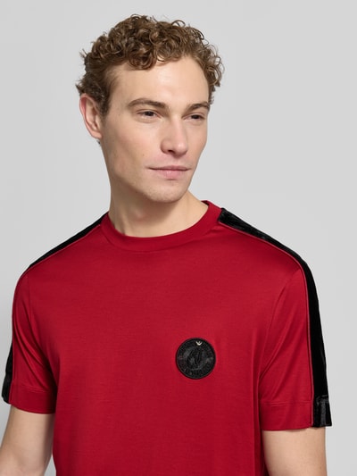Männermodel trägt T-Shirt mit Label-Detail von Emporio Armani in Rot, Lyocell-Baumwoll-Mix, Regular Fit, gerippter Rundhalsausschnitt, Nahaufnahme Oberkörper. Rückenlänge bei Größe M: 70 cm.