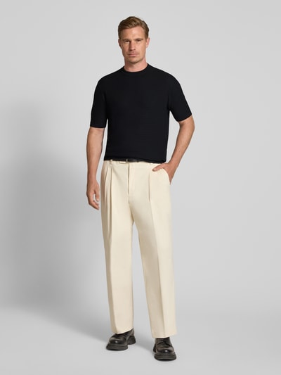 Männermodel trägt Slim Fit Strickshirt aus reiner Wolle von Emporio Armani in Schwarz mit gerippten Abschlüssen, Ganzkörperansicht von vorne.