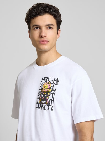 Męski model ma na sobie męski t-shirt z bawełny z nadrukiem, krój relaxed fit, model 'HATTY MAN' od Edwin, okrągły dekolt, kolor biały, długość tyłu w rozmiarze m: 73 cm, zbliżenie na górę ciała z przodu