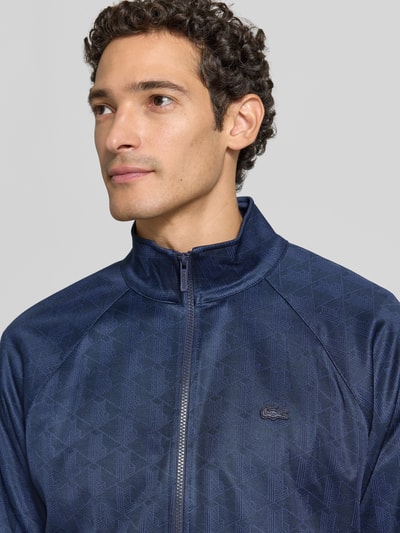 Männermodel trägt Regular Fit Sweatjacke mit Logo-Patch von Lacoste in Dunkelblau mit feiner Struktur, Nahaufnahme Oberkörper, Herren Sweatjacke von Lacoste.