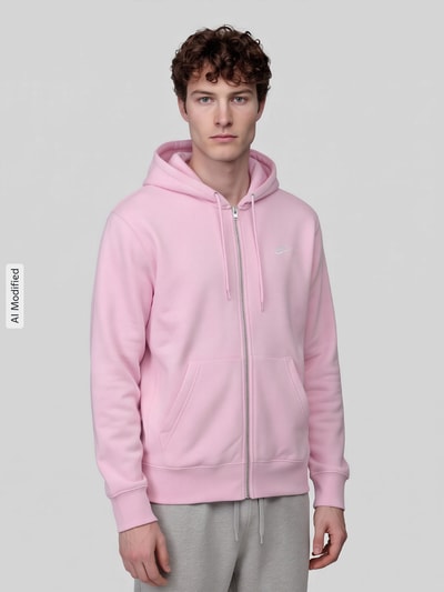 Männermodel trägt Regular Fit Sweatjacke aus Baumwoll-Mix von Nike in Hellrosa mit Reißverschluss und Kapuze, Ganzkörperansicht von vorne, KI-modifiziertes Bild.