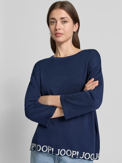 Frauenmodel trägt Strickpullover mit Label-Details und 3/4-Arm Modell 'Kussa' von JOOP! im Viskose-Mix, navyblau, Nahaufnahme Oberkörper.